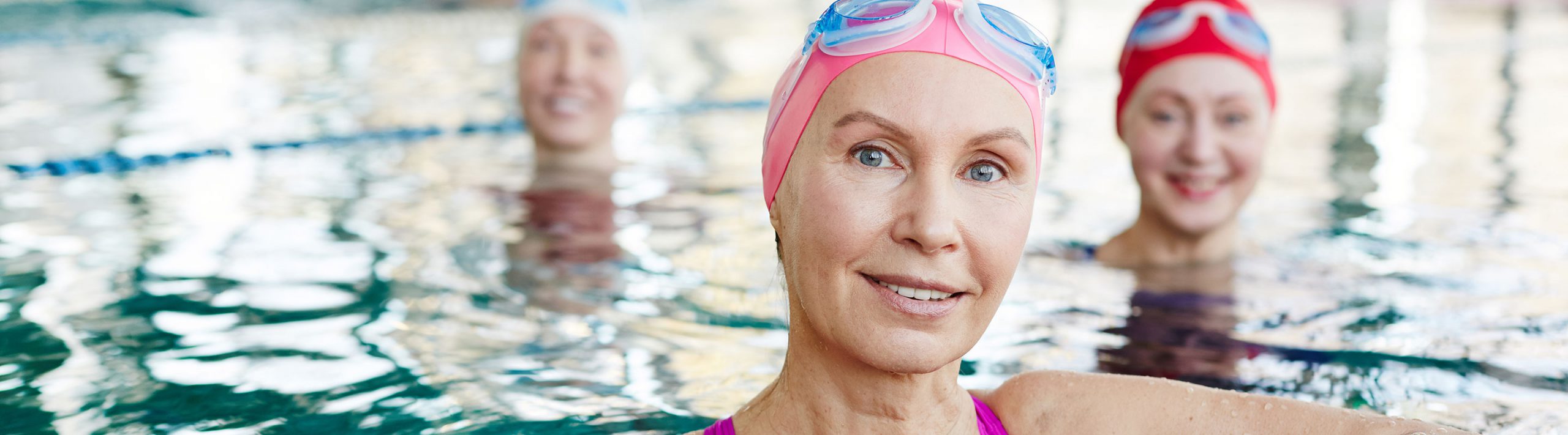Women in the pool with caps and googles.