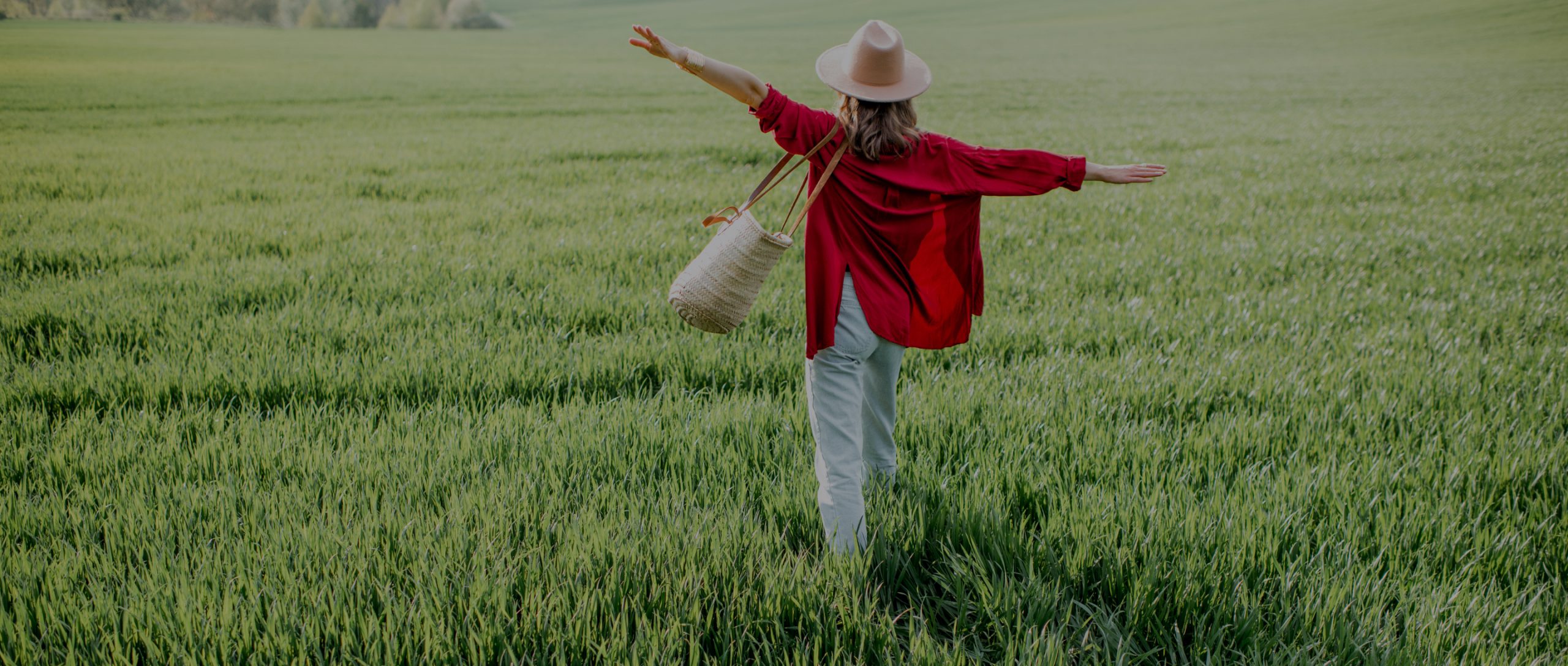 Woman in bright red shirt walks through field.