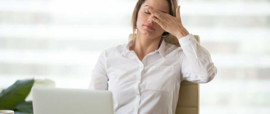 women sitting on her office chair touching her head