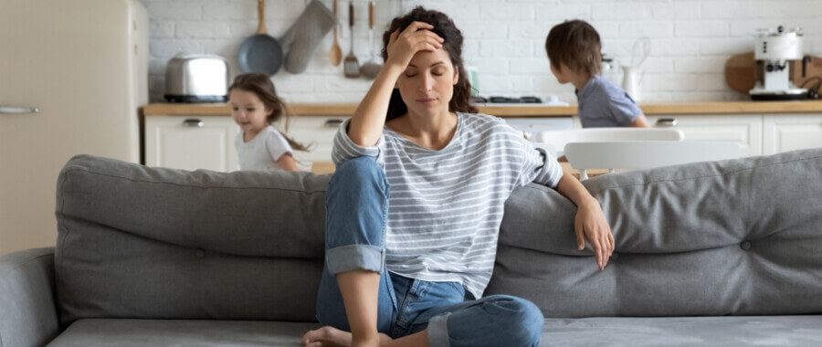 Women sitting on a couch appearing to have a migraine