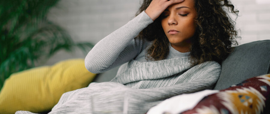 women laying on couch with hand over head