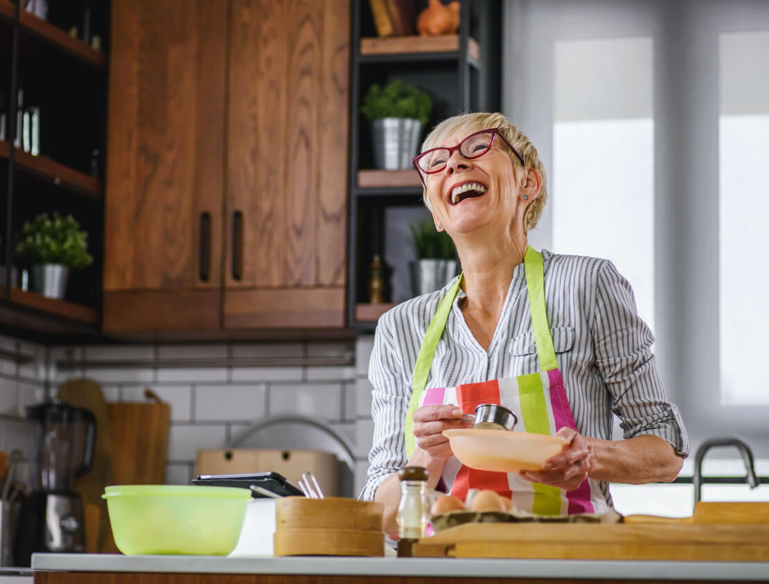 Laughing woman cooking in the kitchen.