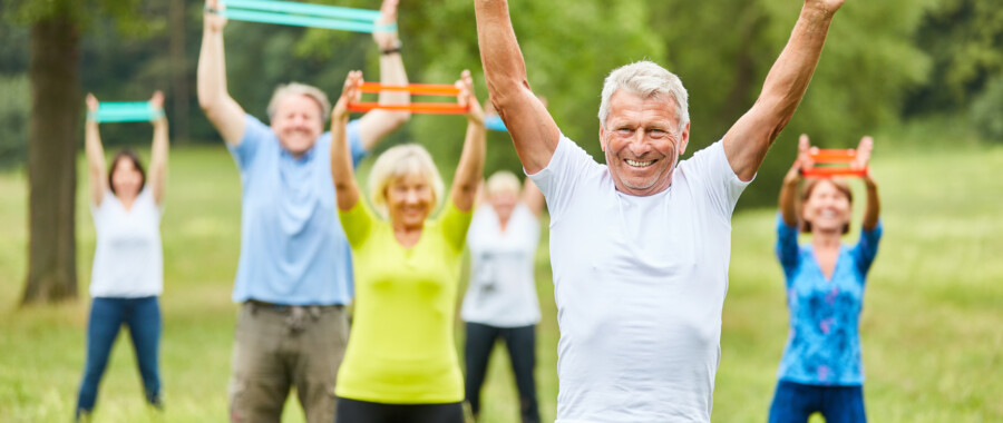 Group of people doing exercise routine outdoors to combat chronic stress.